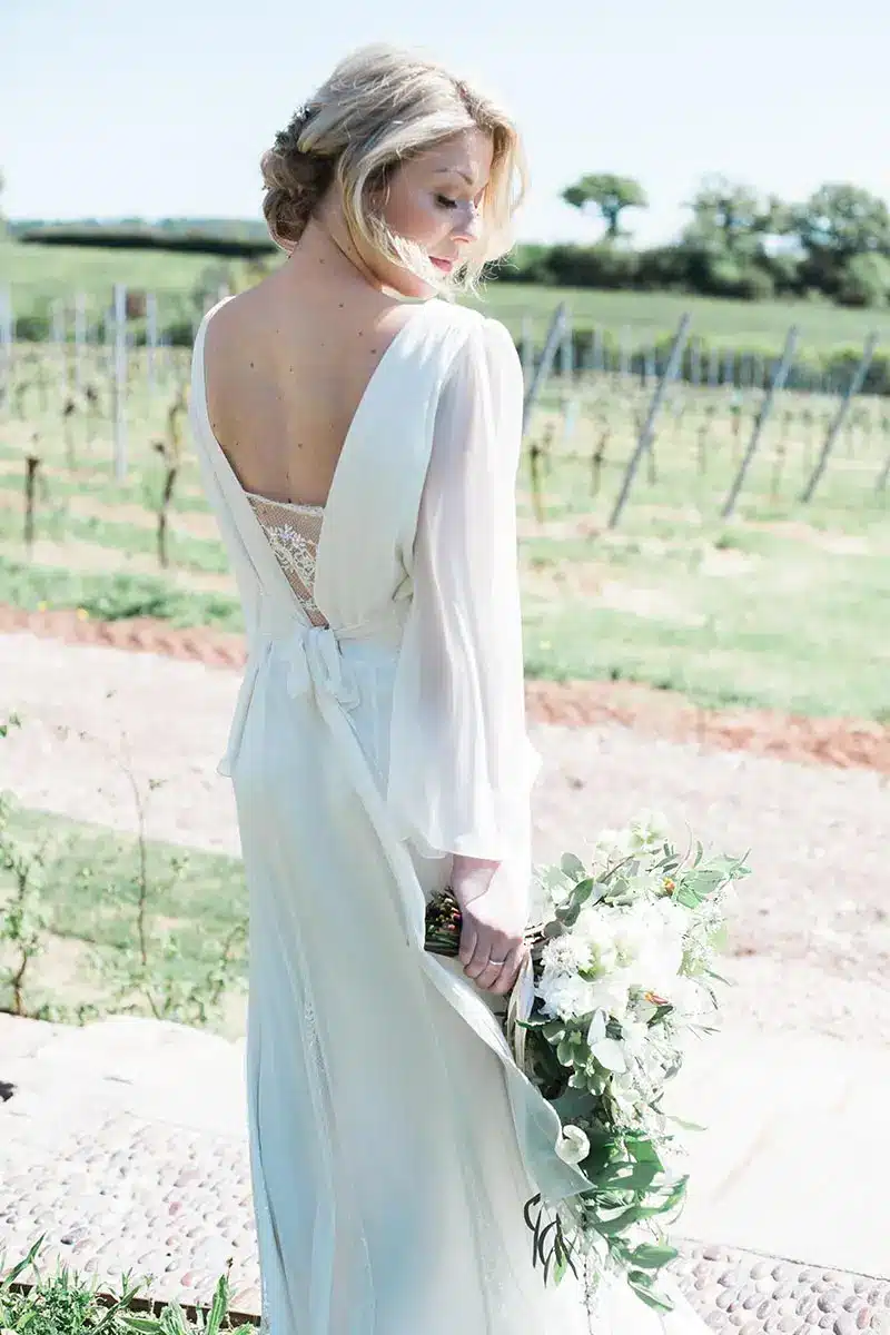 Bride standing on the bridal walk holding a natural flowers bouquet on her small intimate wedding day